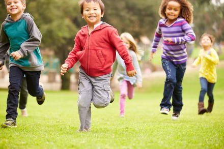 Des enfants, filles et garçons, de races différentes, courent dans un champ