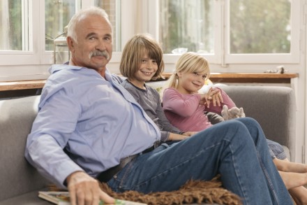 Un papy avec deux enfants assis dans un canapé