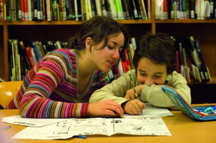 Jeune bénévole aide un petit garçon à faire ses devoirs.
